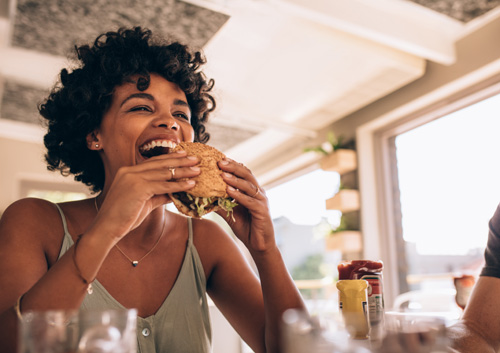 Woman enjoying eating burger at restaurant